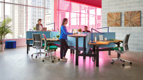 people standing and sitting at height-adjustable desks
